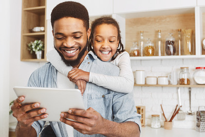 Man and child looking at a device smiling