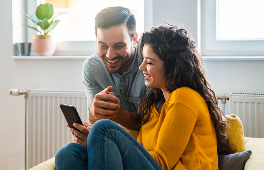 Two people sat in a living room looking at a phone
