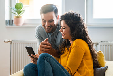 Two people sat in a living room looking at a phone