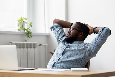 Person sitting back in their chair with their hands behind their back