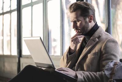 Confused man looking at laptop