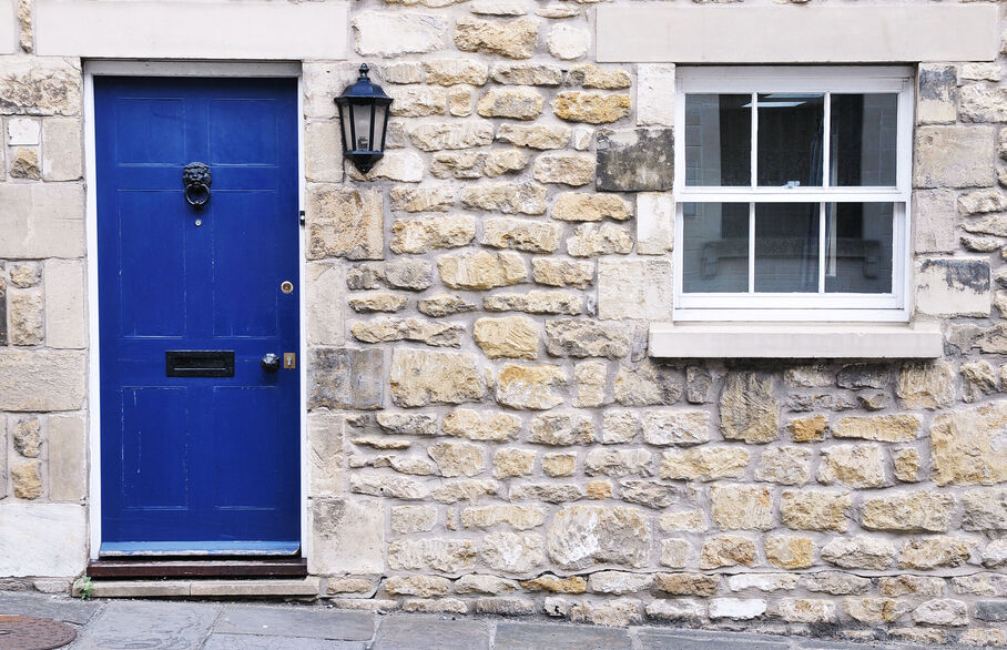 Front of a stone built house with closed blue door