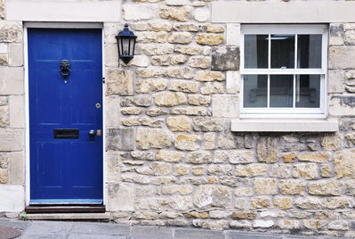 Front of a stone built house with closed blue door