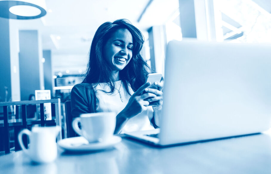 Girl on her phone whilst looking at a laptop