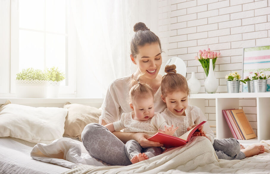 Family sat on the bed reading a book