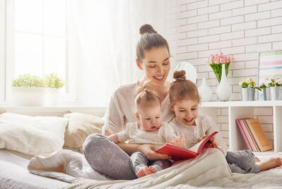 Family sat on the bed reading a book