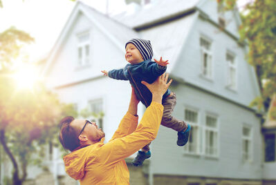 Man playfully throwing his son up in the air