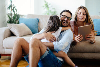 Family cuddled up and looking at an ipad