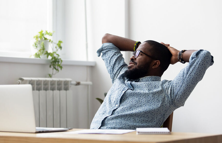 Person leaning back in their chair with hands bhind their head