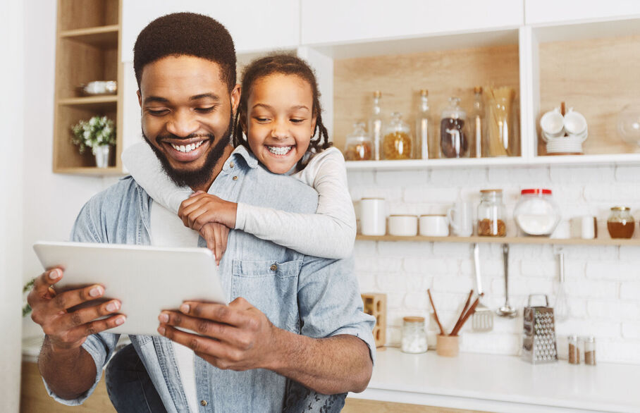 Child on persons back looking at a tablet computer