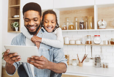 Child on persons back looking at a tablet computer