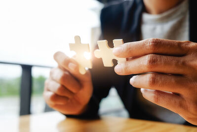 Person putting two pieces of a jigsaw piece together