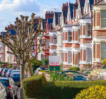 A miniature toy house with coins stacked by the side and a man writing on a notepad