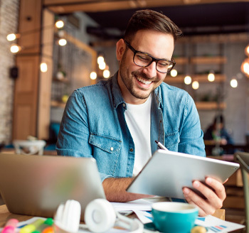 A woman using a laptop smiling at her phone