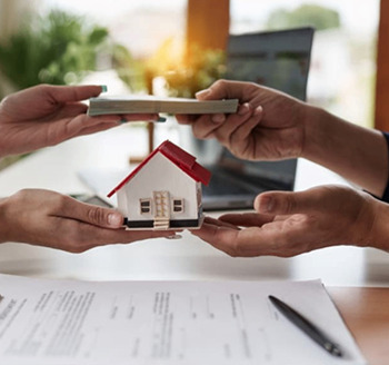 Two hands exchanging a miniature house and money